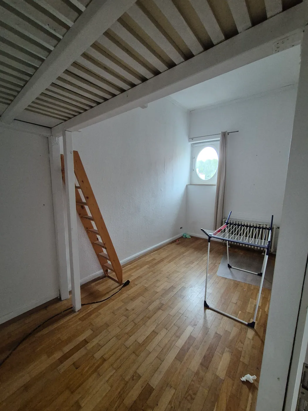 Zimmer mit rundem Fenster und Aufgang zum Hochbett